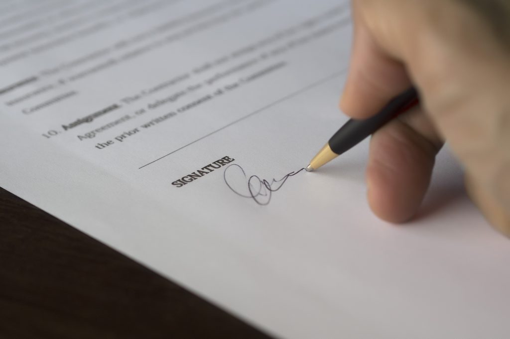 Hand signing document representing Certificate of Status