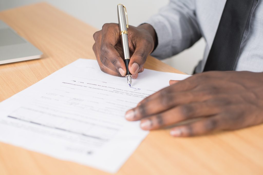 A person signing a document, representing a letter of authorization apostille