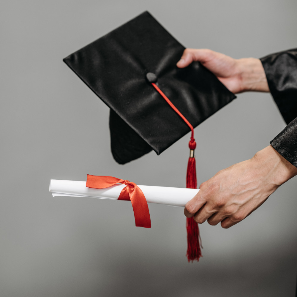 Hands holding diploma and graduation cap, representing link to diploma/transcript authentication page