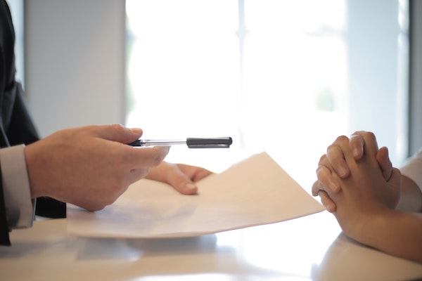 Hands holding a pen and paper, representing a power of attorney apostille
